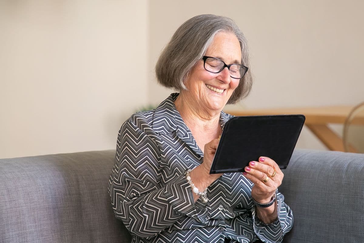 A smiling senior woman using a tablet at home
